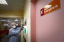 Enfermeira paramentada higienizando as mãos com álcool no corredor de emergência do Hospital do Trabalhador