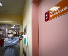 Enfermeira paramentada higienizando as mãos com álcool no corredor de emergência do Hospital do Trabalhador