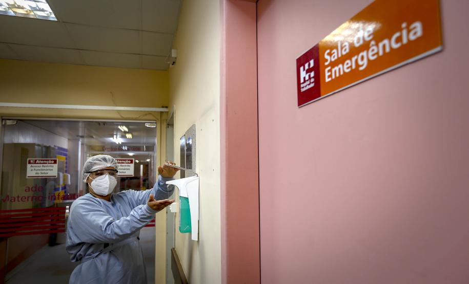 Enfermeira paramentada higienizando as mãos com álcool no corredor de emergência do Hospital do Trabalhador